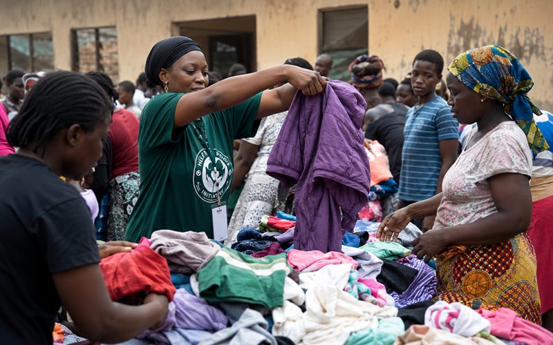A Help The Poor Initiative volunteer handing out clothing at a distribution