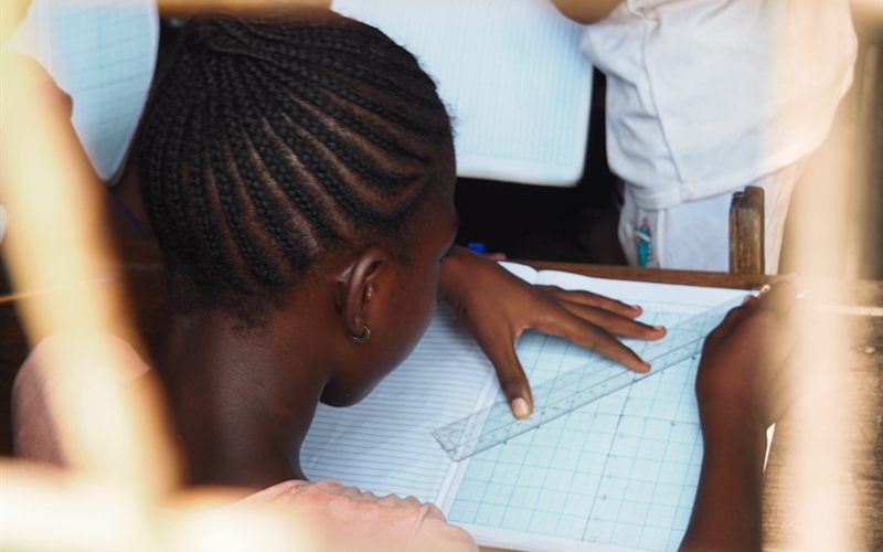 A pupil in school uniform working at her desk in class